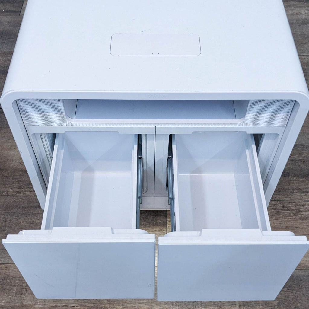 Open drawers of white cabinet, showcasing storage compartments for beverages and snacks.