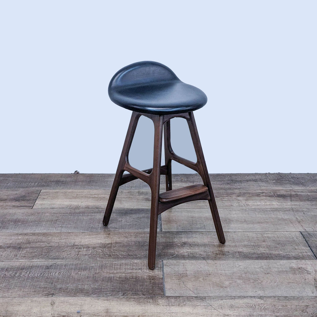 Side view of a black leather-look barstool with a sturdy wood frame.