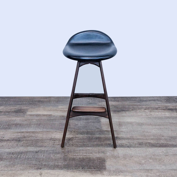 Barstool with black padded seat on a wooden frame, on a wooden floor.