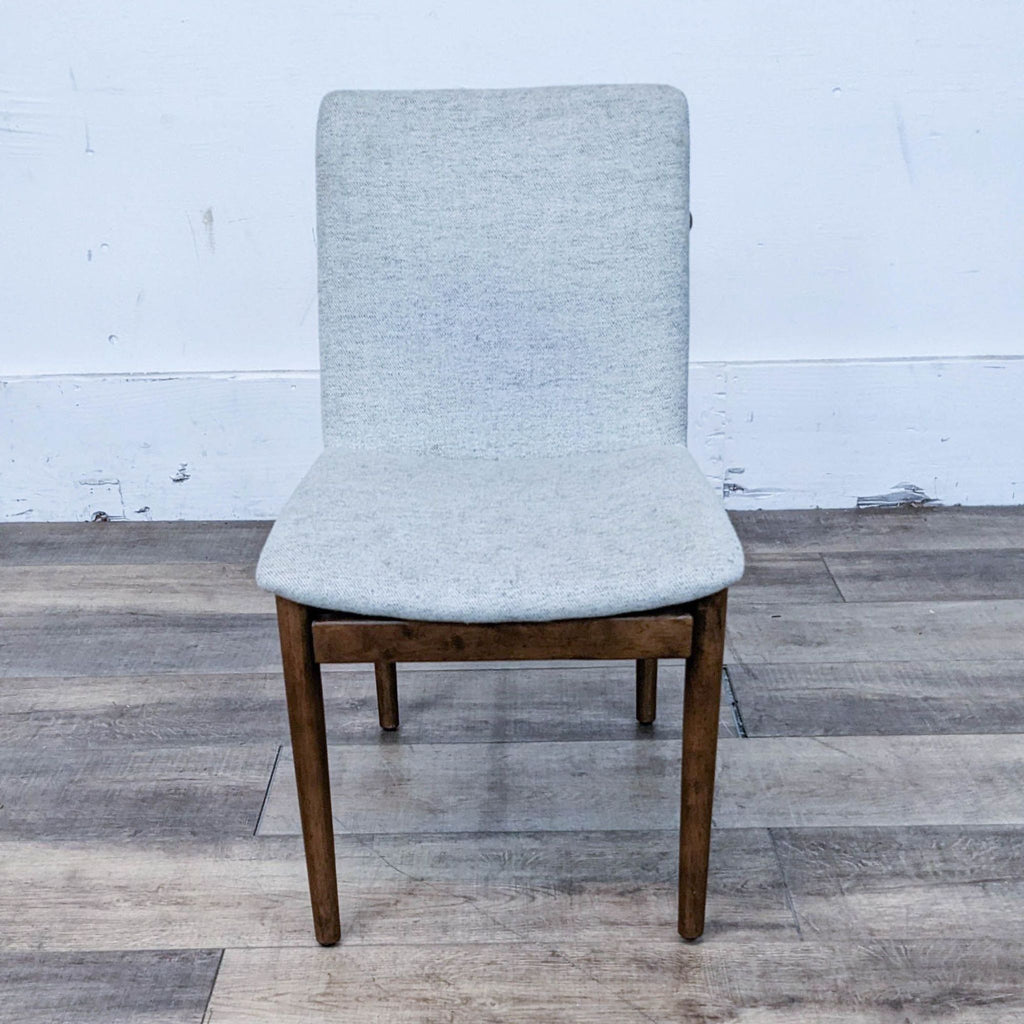 Dining Chair designed by West Elm, featuring a walnut wood frame and a padded upholstered seat.