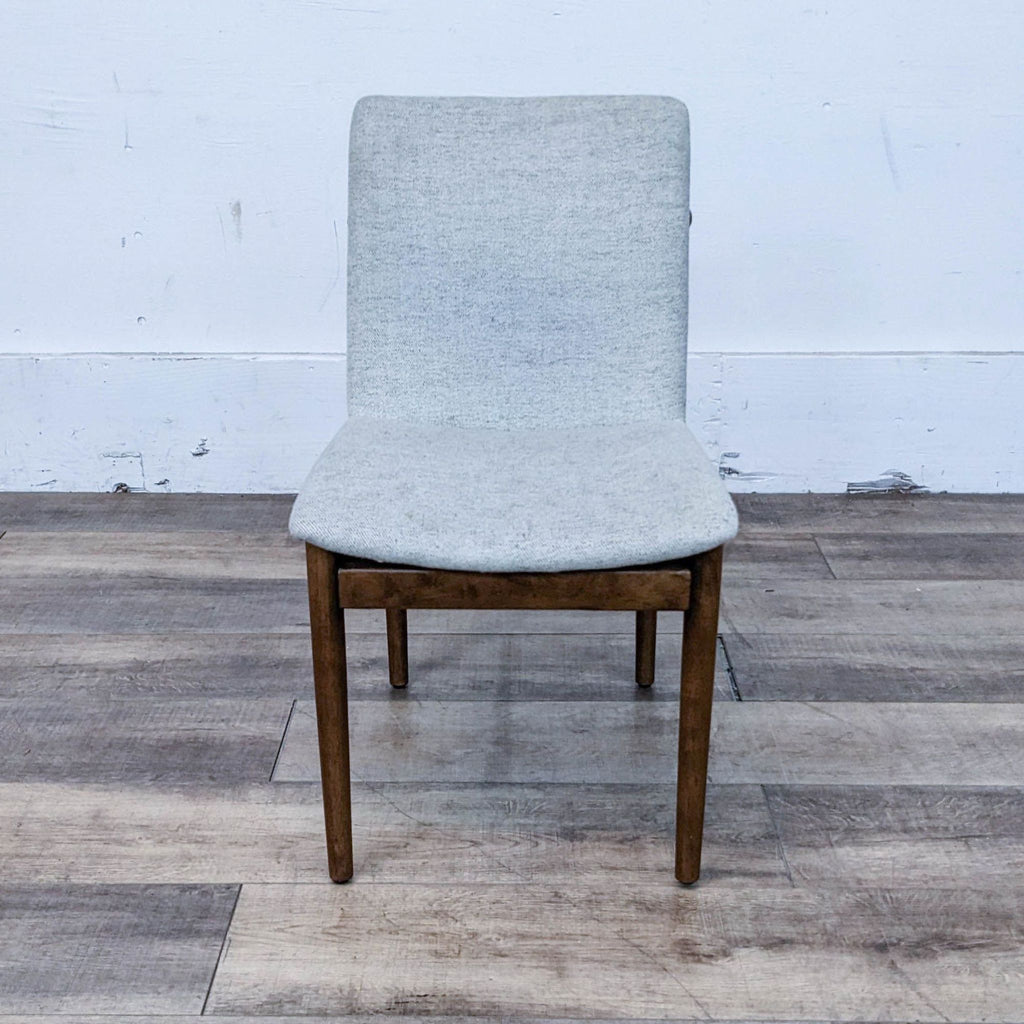 Front view of the Framework Dining Chair with walnut wood frame and light upholstered seat by West Elm.
