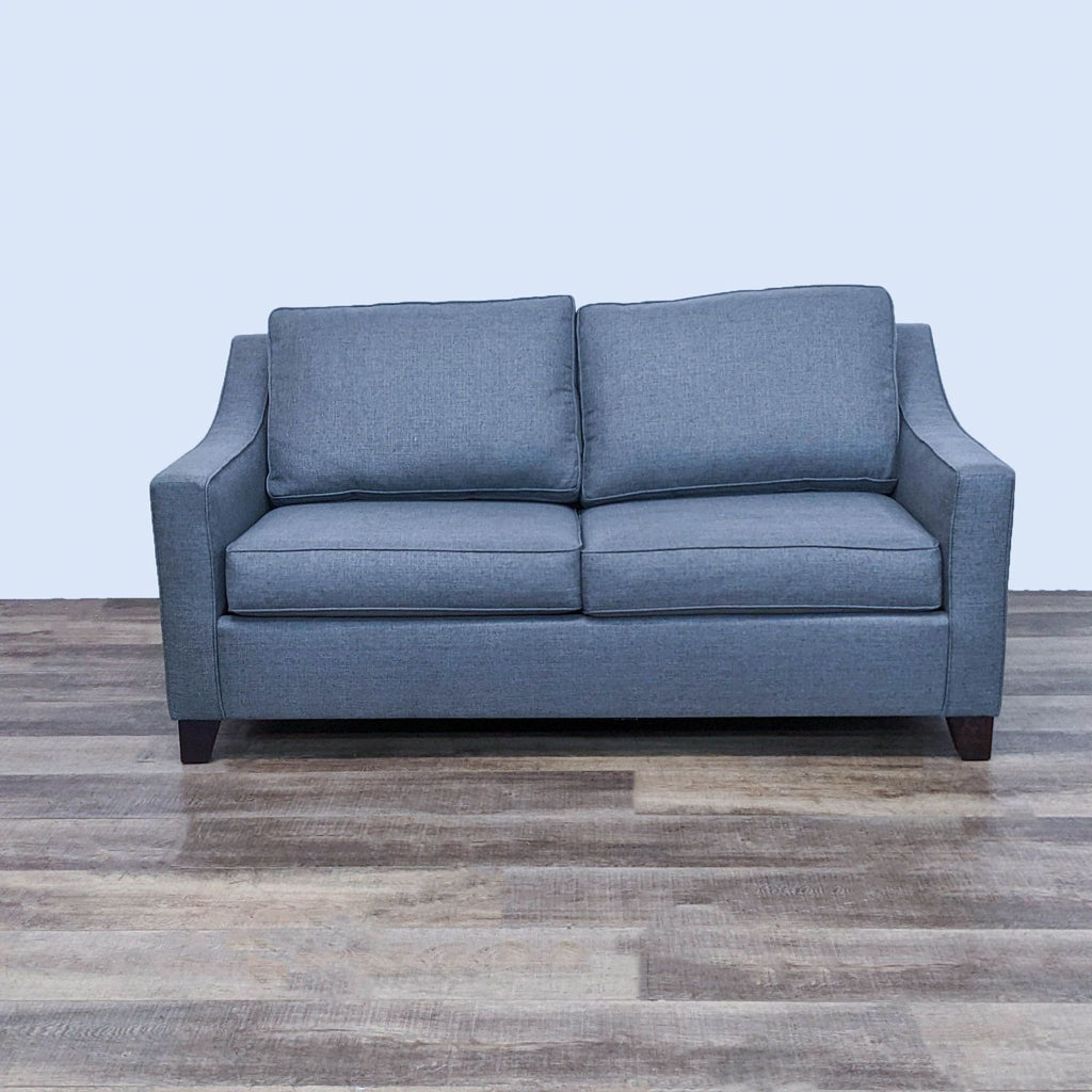 Gray sleeper sofa with slope arms and dark feet, shown from the front on wooden floor.