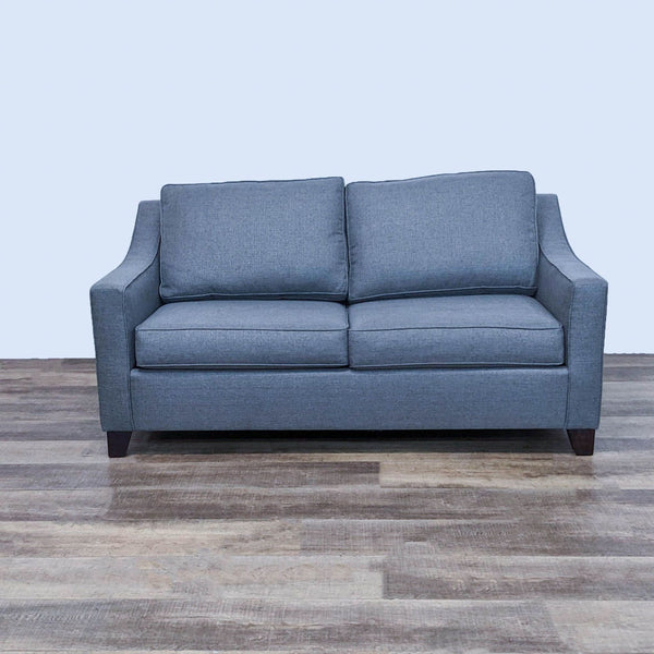 Gray sleeper sofa with slope arms and dark feet, shown from the front on wooden floor.