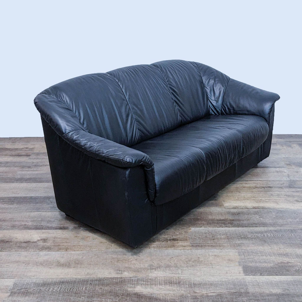 Side view of Reperch black leather sofa with curved pillow top arms.