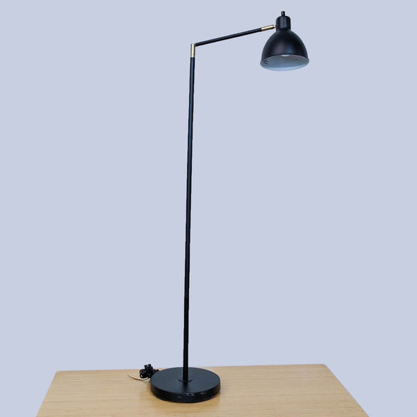 1. Black floor lamp with adjustable arm on wooden table by Reperch.