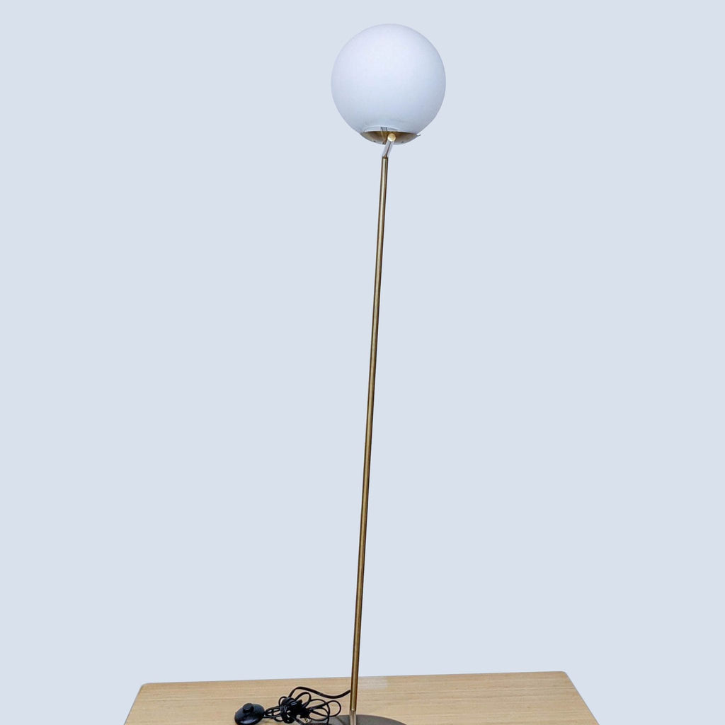 Minimalist brass floor lamp with a spherical light by Reperch.