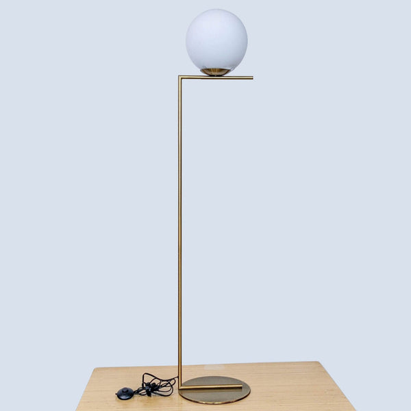 Modern lamp by Reperch with a globe light on a sleek brass stand.  