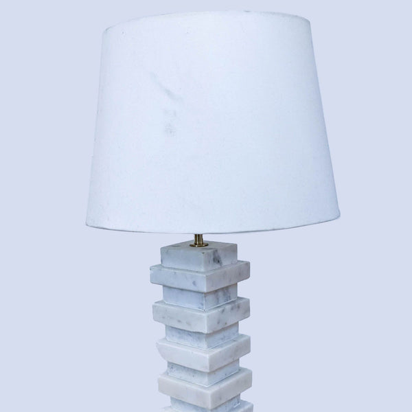 Reperch stacked marble lamp with white shade on a light wooden table.