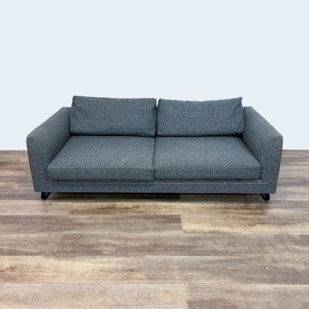 Ersa dark gray sofa with brown piping, front view on wooden floor.