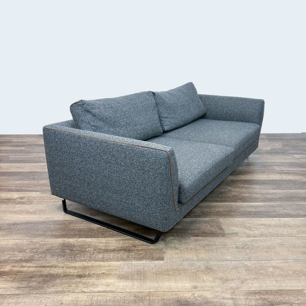 Dark gray 3-seat sofa with brown leather piping on metal frame, viewed from an angle.