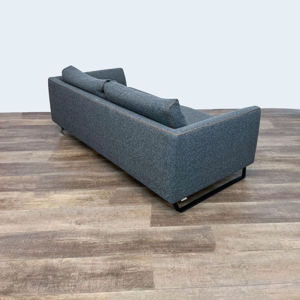 Back view of gray metal-framed sofa with brown leather accents.