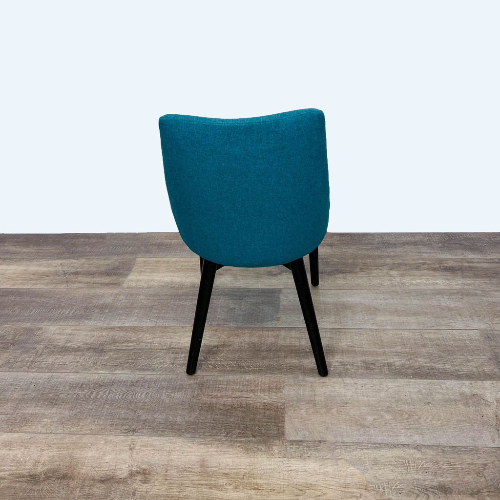 Back view of a teal chair with sleek black wood legs.