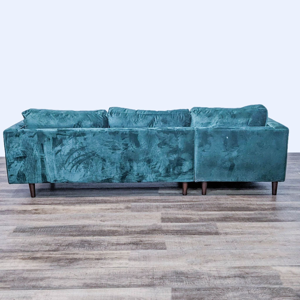 Back view of green velvet sectional, highlighting its simple, elegant design.