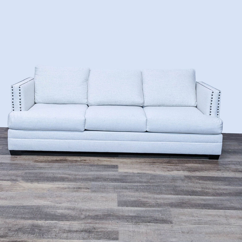 Track arm sofa with nailhead detailing and dark finish feet in light fabric.
