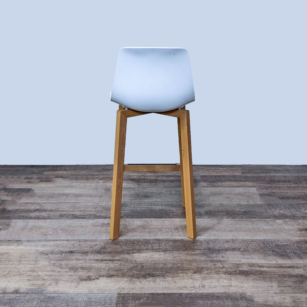 Back view of a stool featuring a molded white seat and wooden base.