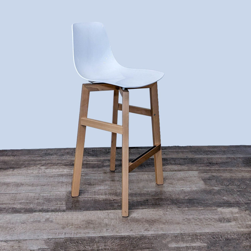 Side view of a white plastic stool with solid wood legs and base.