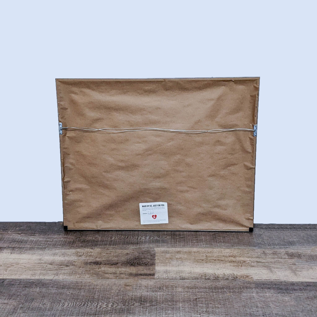 Back of a framed floral painting from Art.com, showing hanging hardware and brown paper backing.