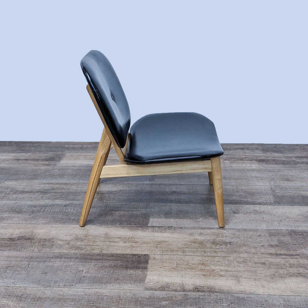 Side view of a Mid-Century style chair, featuring clean lines and faux leather upholstery, by Reperch.