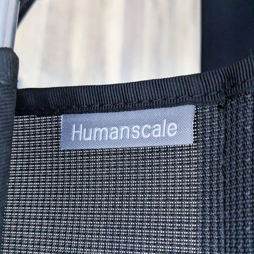 Close-up of the Humanscale brand label on a black textured fabric.