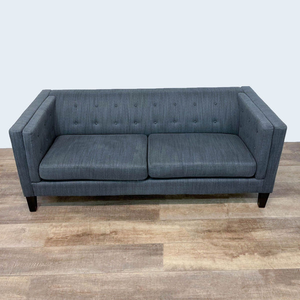 Gray tufted back sofa with dark legs on wooden floor.