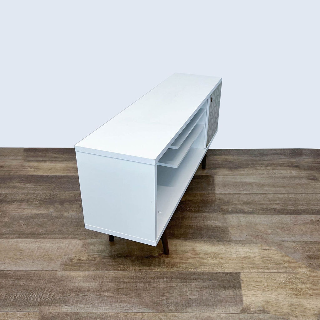Sleek white entertainment center by Reperch with tapered legs and geometric design on the door.