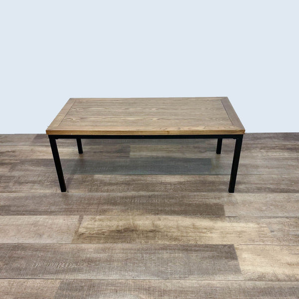 Reperch coffee table with a wooden top and black metal legs on a wooden floor.