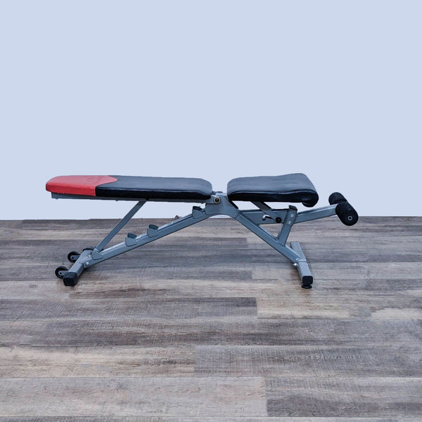 1. Adjustable Bowflex gym bench in a flat position on a wood floor background.