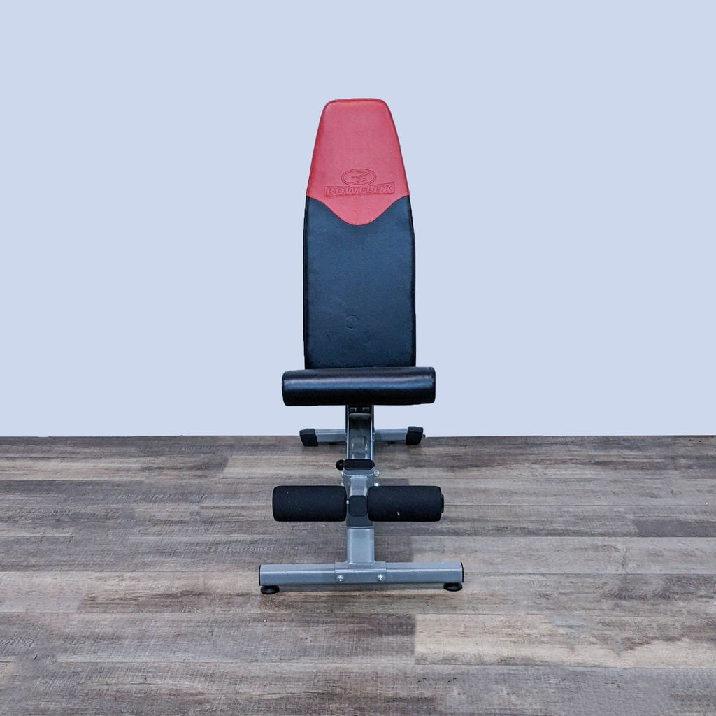 3. Front view of a Bowflex gym bench with red and black padded backrest for strength training.