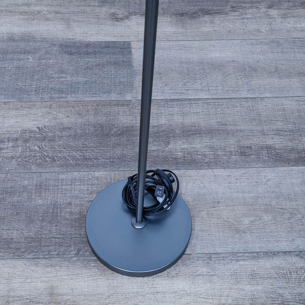 Close-up of the lamp's sturdy round base with a coiled cord.