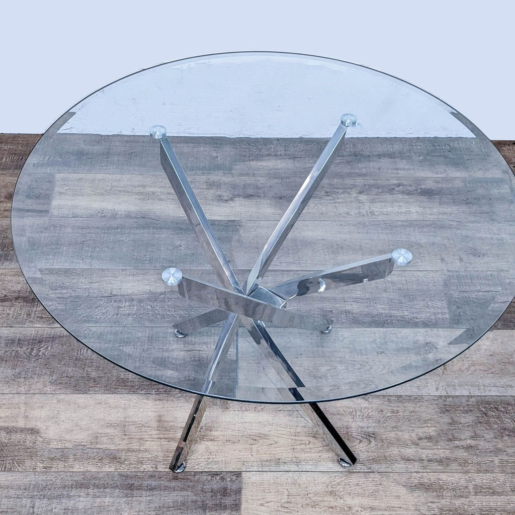Round glass dining table with sculptural chrome base and small leveler feet for stability.