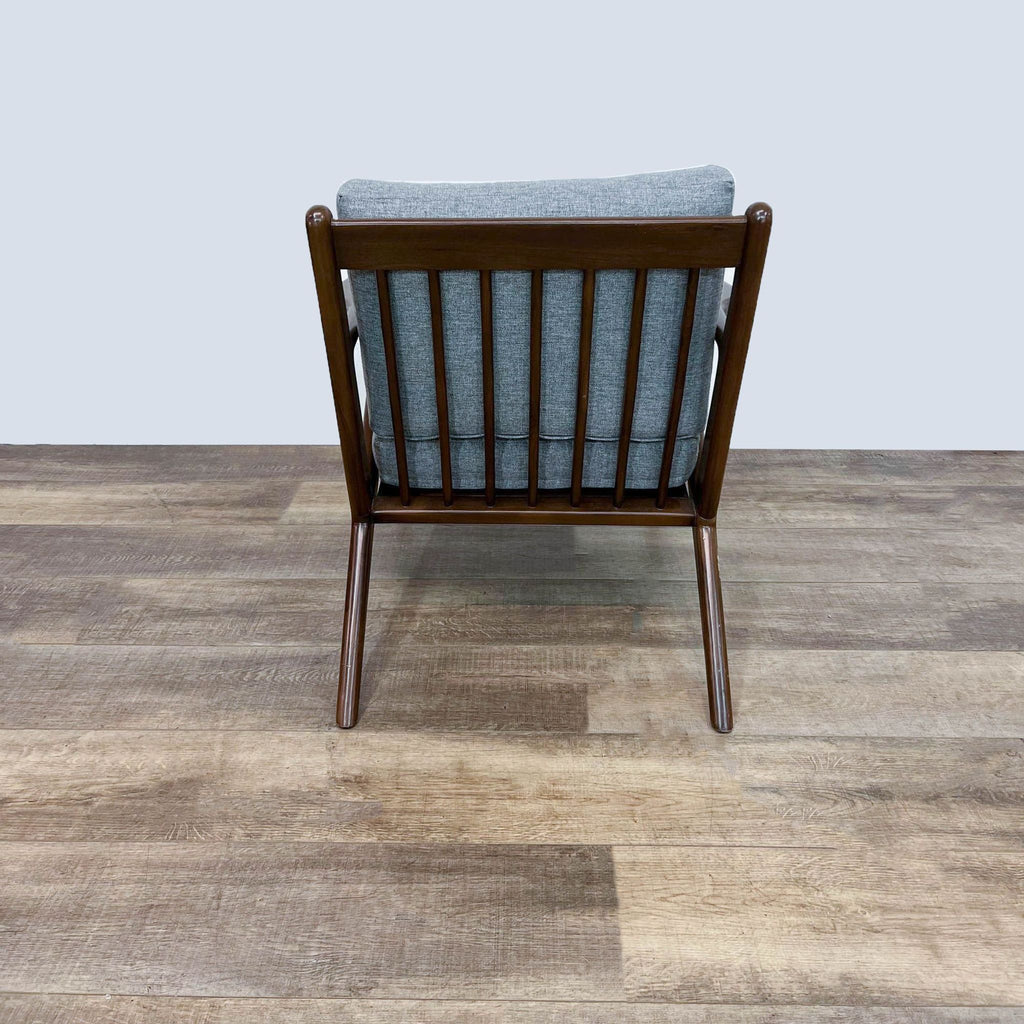 Back view of chair showing wooden frame and gray cushions.