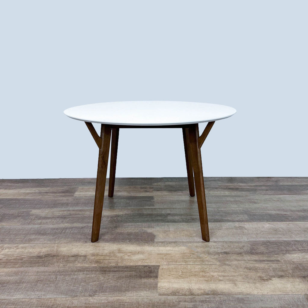 Wegmans Furniture dining table with a white round top and wood legs in Scandinavian style.