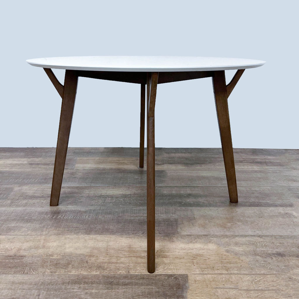 Scandinavian design dining table with a modern feel, white round top, and four solid wood legs.