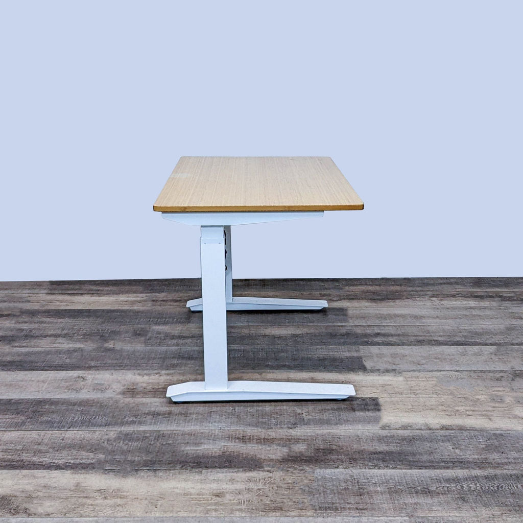 Bamboo top Jarvis desk on white frame, shown on wooden floor.