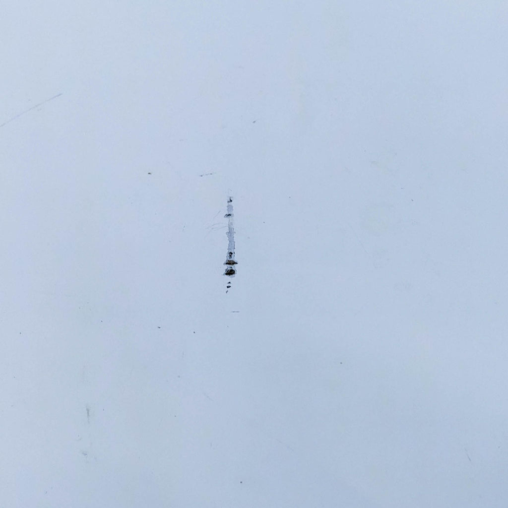 Close-up of a blemish on a white surface, showing small marks and scratches.