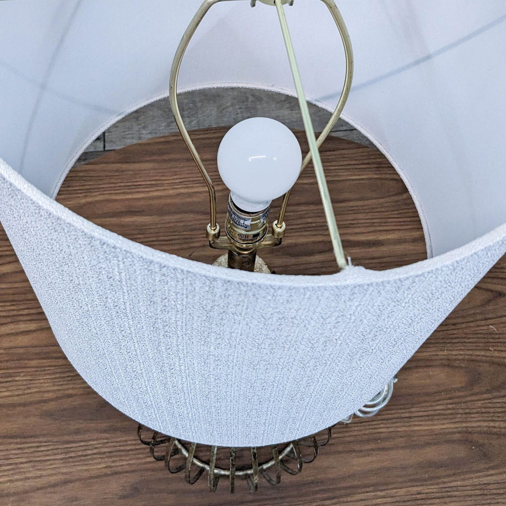 Top view of a table lamp showing the light bulb and textured white shade.