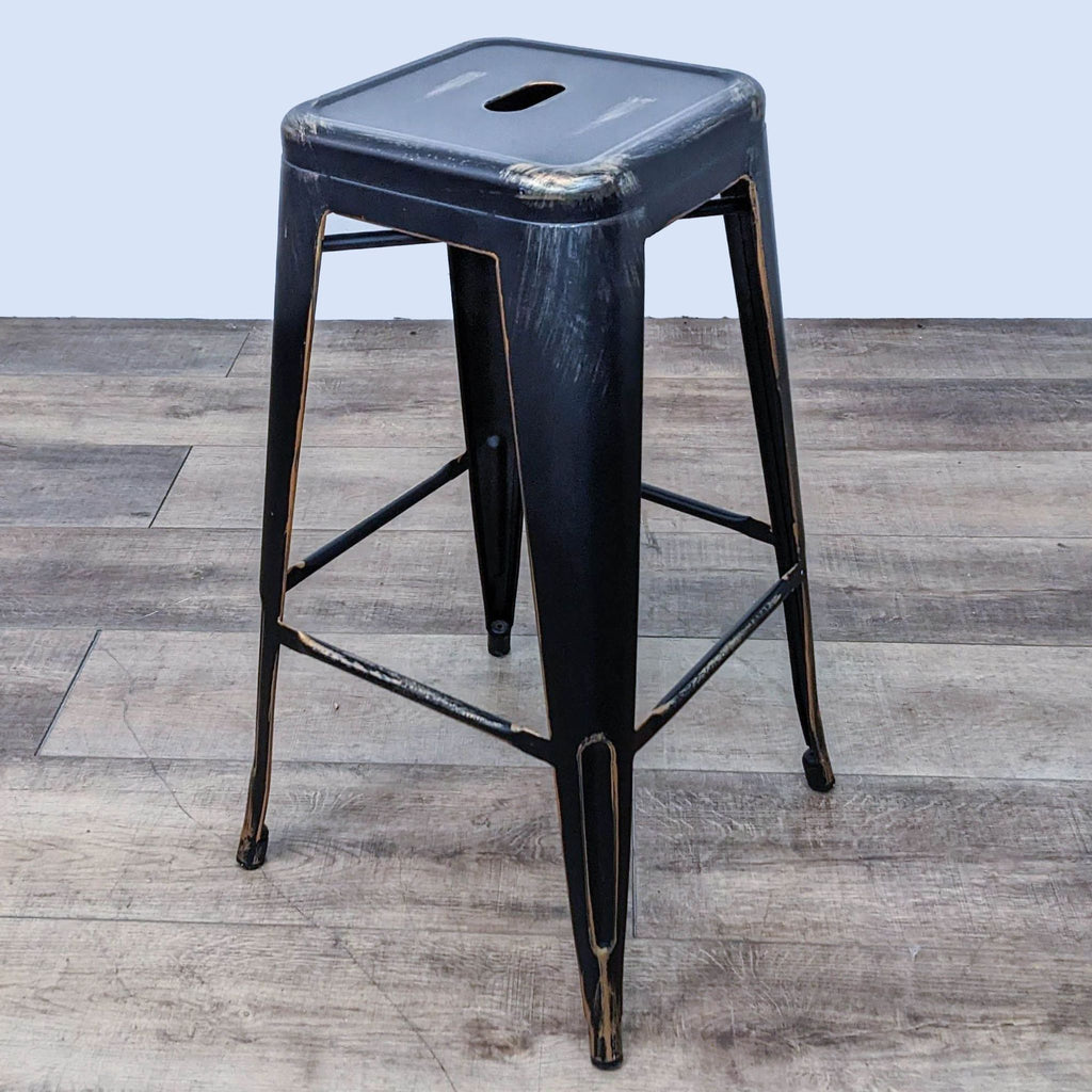 Black metal barstool with gold accents and unique seat cutout design.