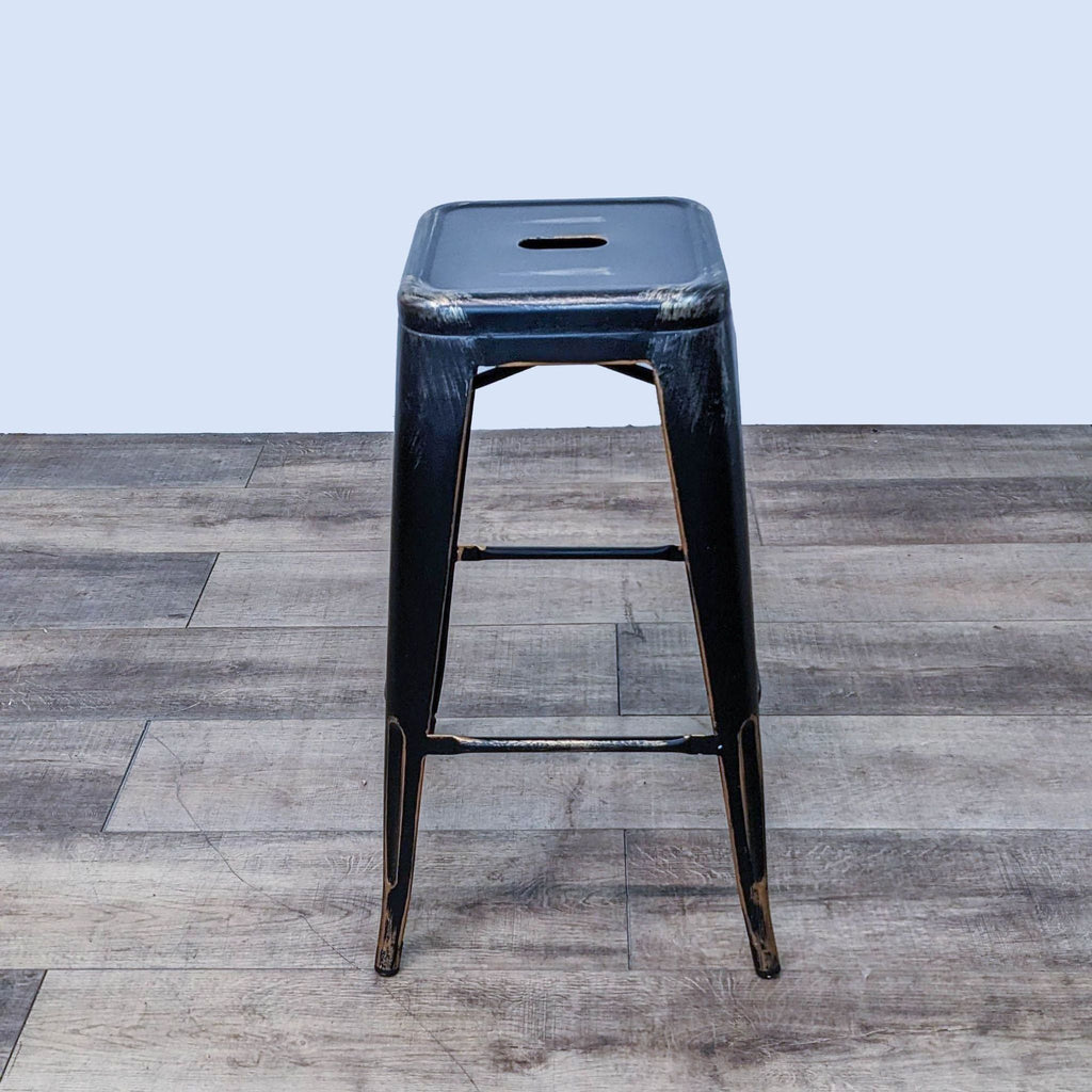 Industrial black metal barstool with gold details and cutout seat design.