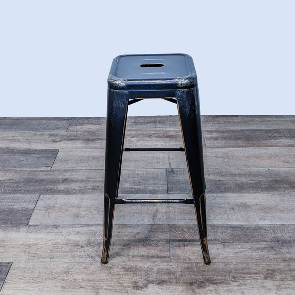 Industrial black metal barstool with gold details and cutout seat design.