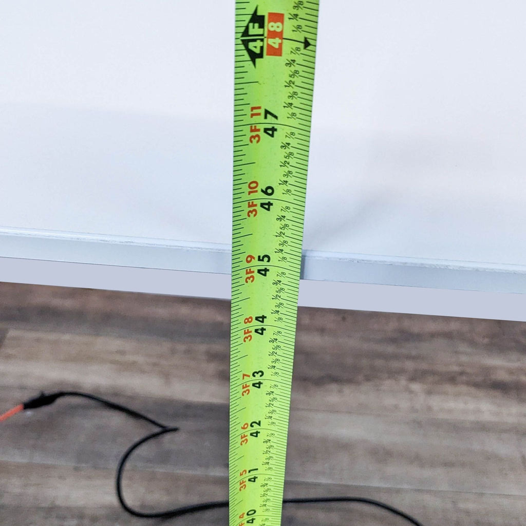 Close-up of a tape measure showing desk height in inches.