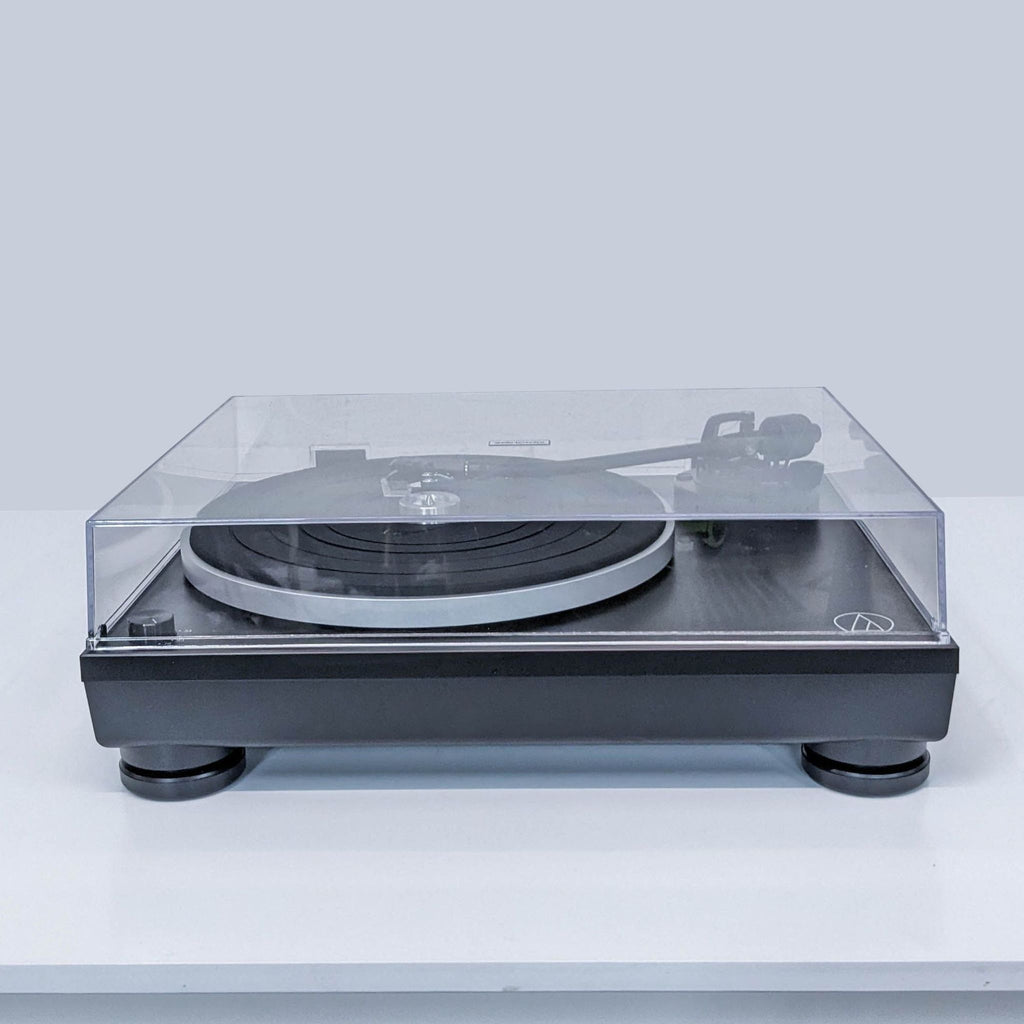 1. Audio-Technica turntable with transparent dust cover, shown from the front on a white surface.