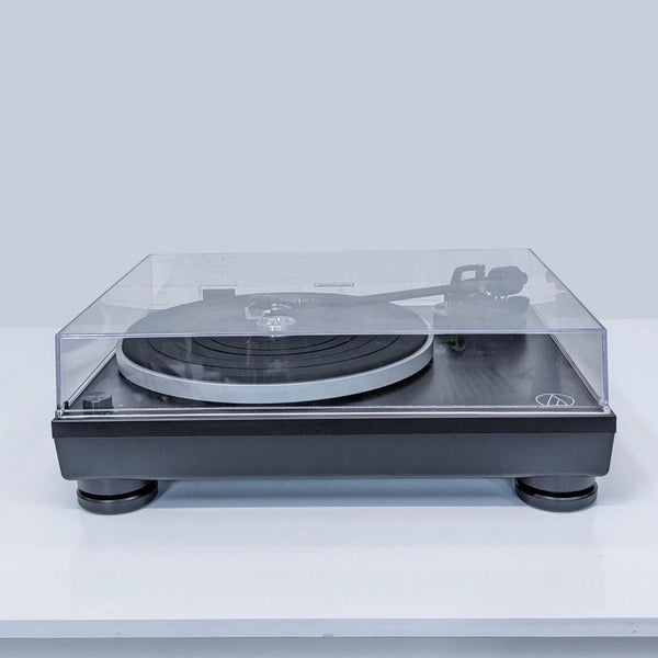 1. Audio-Technica turntable with transparent dust cover, shown from the front on a white surface.