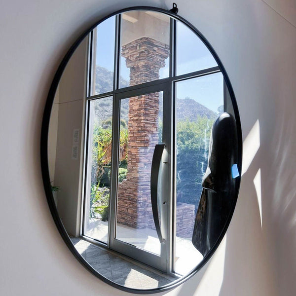 1. Large round wall mirror with a slim black frame by Reperch, reflecting a window scene.