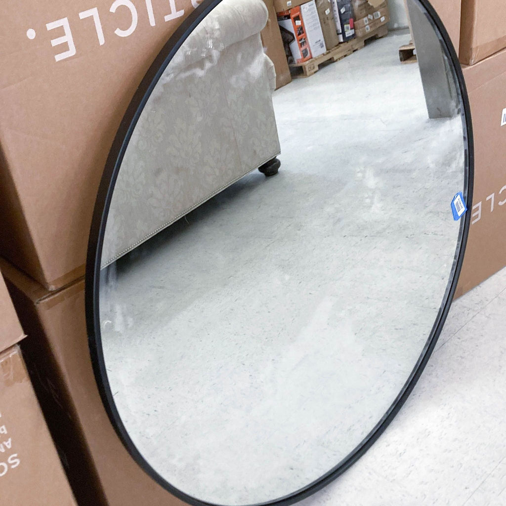 3. Round Reperch mirror with sleek black frame, reflecting a patterned sofa and store boxes.