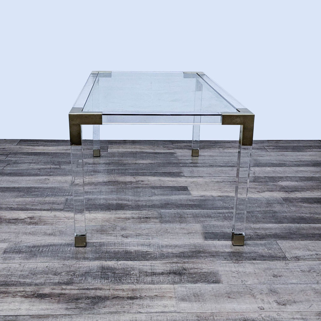 2. Luxe clear acrylic dining table by Jonathan Adler, accented with brushed brass corners, minimalist design.  