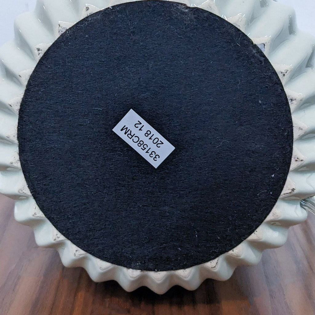 Bottom of Reperch lamp's ceramic base with a felt pad and label sticker.
