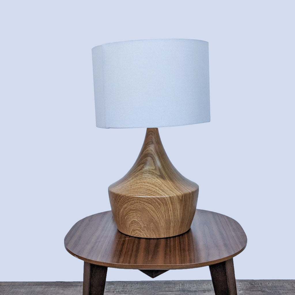 Reperch table lamp with wooden base and white shade on wooden table.