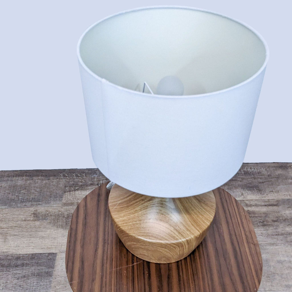 Side view of Reperch lamp on table, showcasing wooden base and white shade.