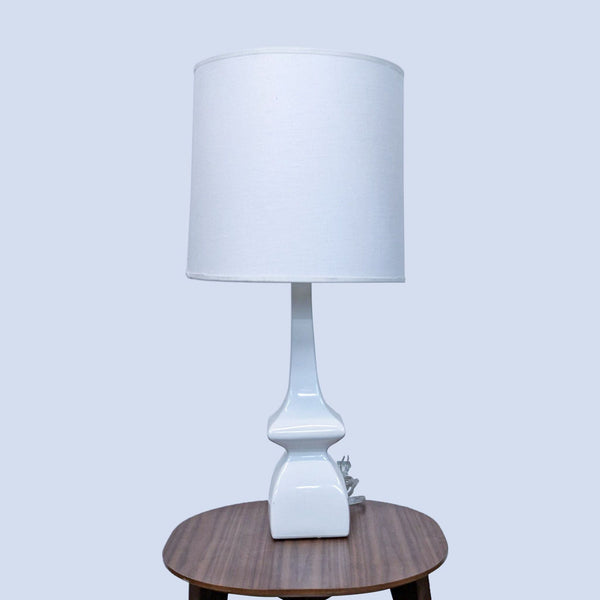 White table lamp with a sleek design and cylinder shade on a wooden surface.
