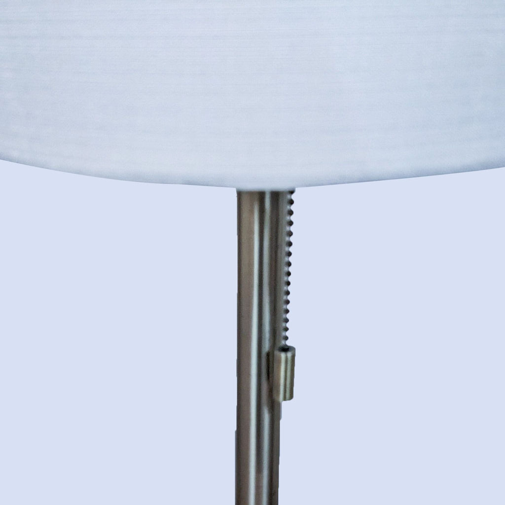 Close-up of the lamp's pull chain and cylindrical white shade on a metal stand.